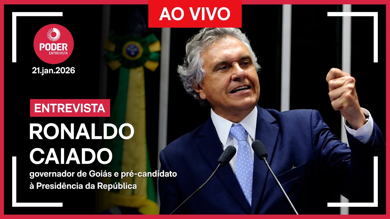 Uma imagem promocional de "Poder Entrevista" para uma entrevista ao vivo com Ronaldo Caiado. Caiado, governador de Goiás e pré-candidato à Presidência da República, está de pé em um púlpito com microfones, com o punho esquerdo fechado em um gesto de ênfase. Ele veste terno azul-escuro, camisa branca e gravata azul-clara estampada. O fundo escuro mostra uma bandeira do Brasil desfocada. O texto na imagem inclui: "PODER ENTREVISTA", "21.jan.2026", "AO VIVO", "ENTREVISTA", "RONALDO CAIADO" e "governador de Goiás e pré-candidato à Presidência da República".